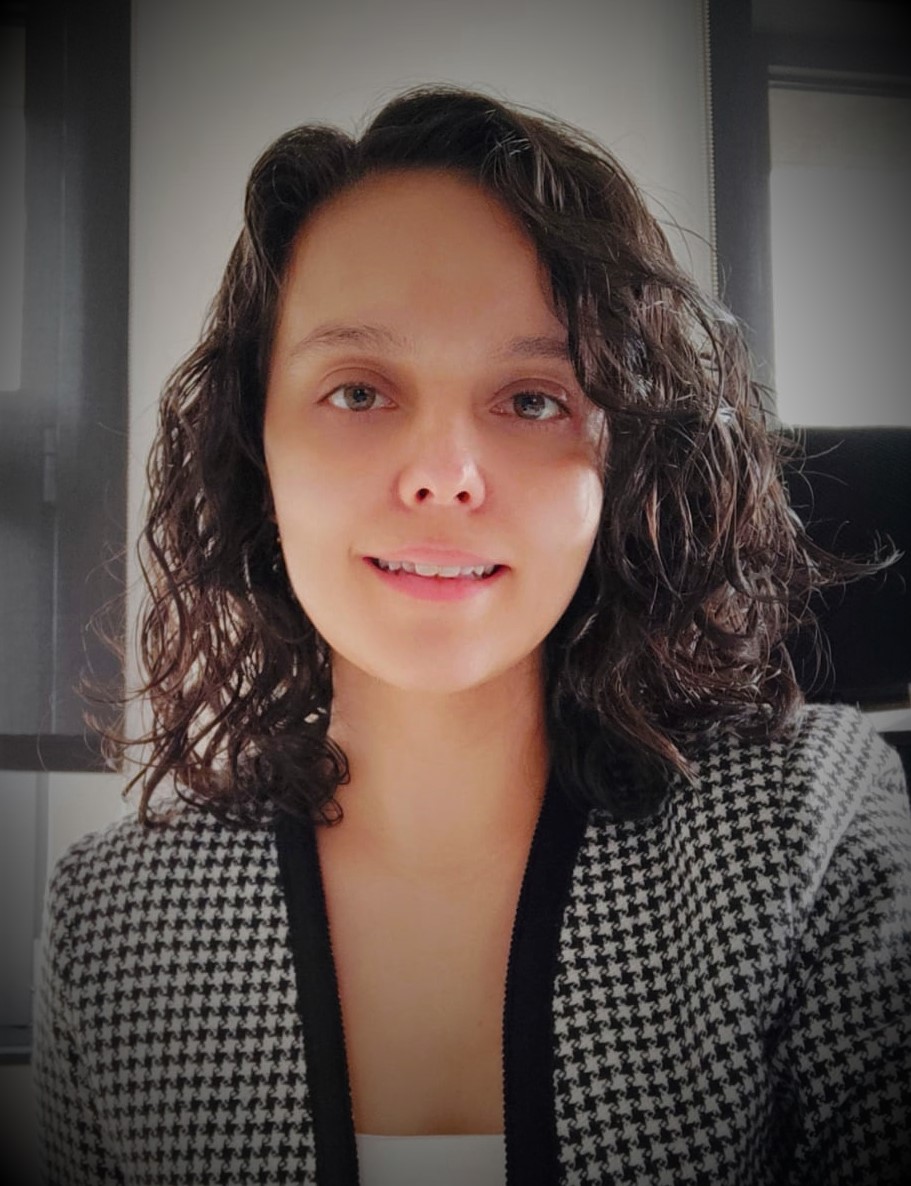 A headshot of a woman with curly, short, shoulder-length hair with green eyes